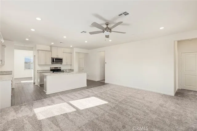a view of kitchen with stainless steel appliances kitchen island sink refrigerator and white cabinets