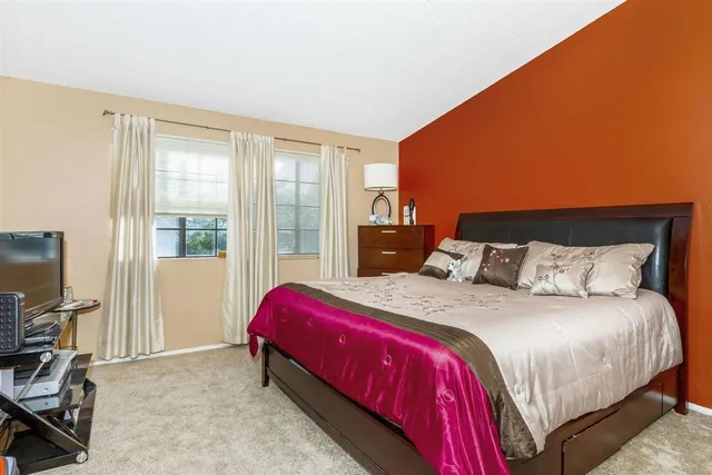 a bedroom with a bed a flat screen tv and windows