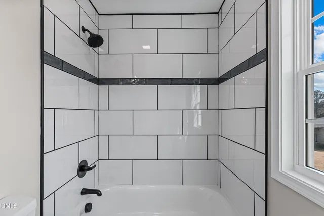 a bathroom with a bathtub shower sink vanity mirror and toilet
