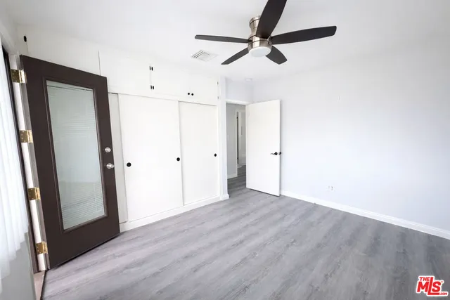 an empty room with wooden floor and ceiling fan
