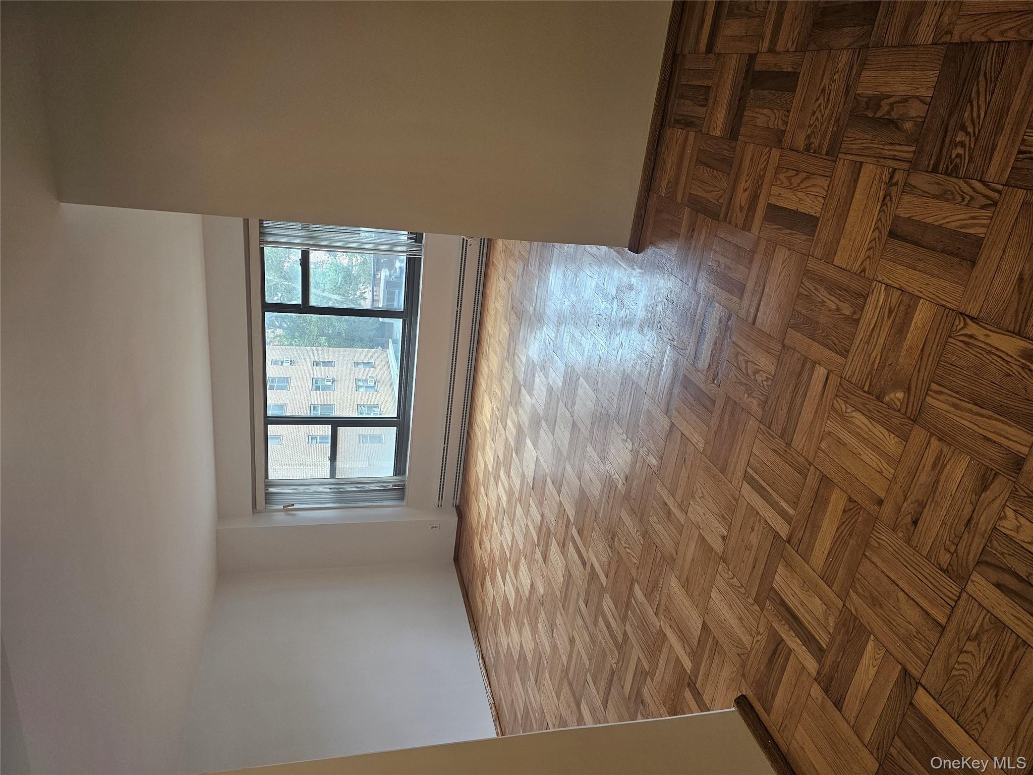 21-85 34th Avenue, Unit 3B Queens, NY 11106 - Photo 1 of 12 an empty room with wooden floor and windows