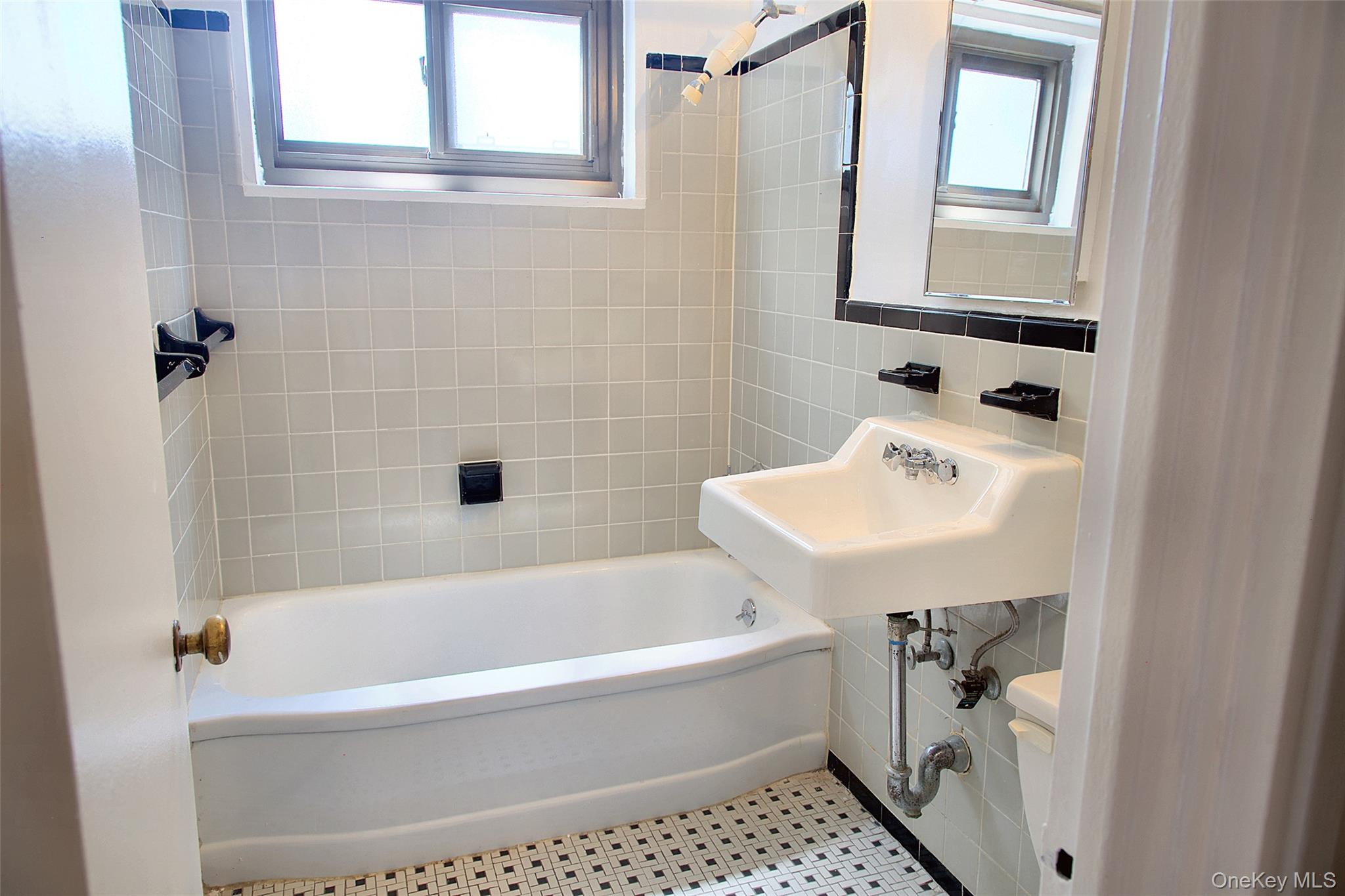 21-85 34th Avenue, Unit 3B Queens, NY 11106 - Photo 8 of 12 a white bath tub sitting next to a white sink and a toilet