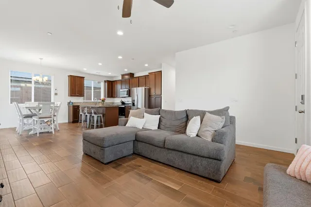 a kitchen with stainless steel appliances granite countertop a stove top oven a sink dishwasher a dining table and chairs with wooden floor