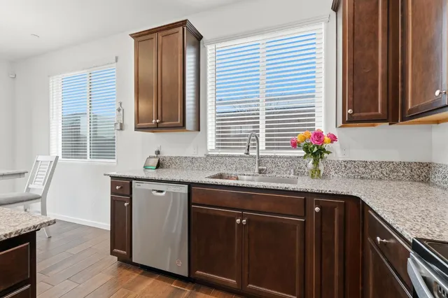 a kitchen with stainless steel appliances granite countertop a sink and wooden cabinets