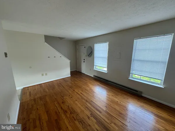 an empty room with wooden floor and windows