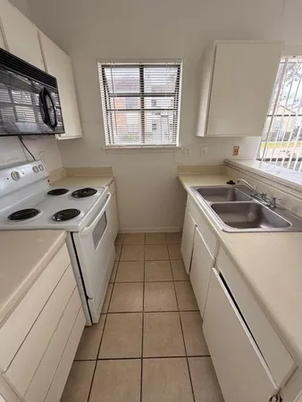 a kitchen with a sink a stove top oven and cabinets