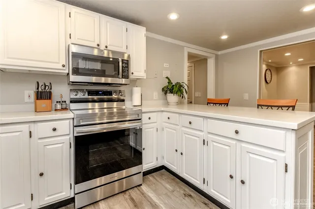 a kitchen with stainless steel appliances white cabinets a sink and a stove