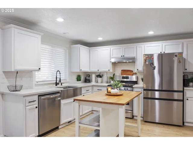 a kitchen with stainless steel appliances a refrigerator sink and white cabinets