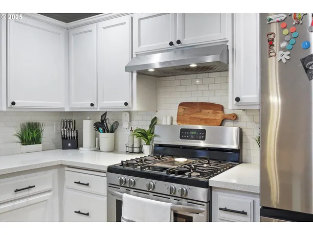 a kitchen with stainless steel appliances granite countertop a stove a white cabinet and a granite countertops