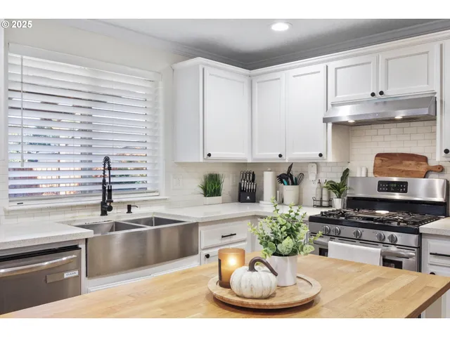 a kitchen with stainless steel appliances a stove a sink and a white cabinets