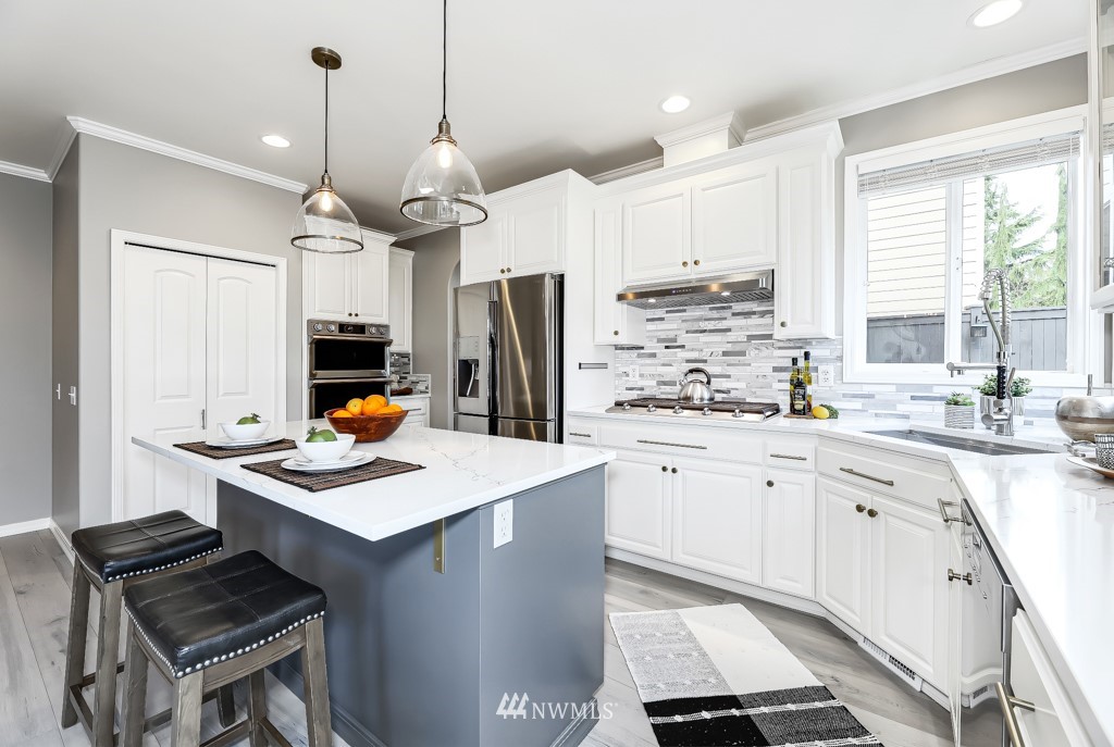 21303 37th Avenue Southeast Bothell, WA 98021 - Photo 6 of 34 a kitchen with stainless steel appliances kitchen island granite countertop a stove a sink dishwasher a refrigerator a microwave oven with cabinets and wooden floor