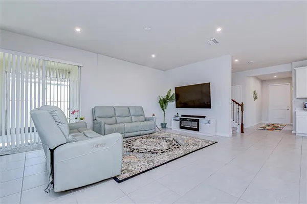 a large kitchen with stainless steel appliances a refrigerator a sink dishwasher a stove and white cabinets with wooden floor