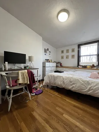 a bedroom with a bed and wooden floor
