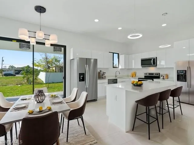 a dining room with stainless steel appliances kitchen island granite countertop a dining table chairs and a refrigerator