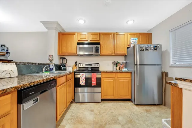 a kitchen with stainless steel appliances granite countertop a refrigerator stove a sink and a microwave