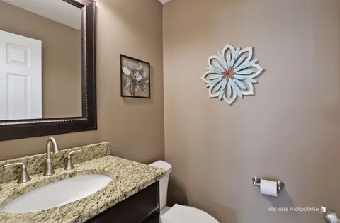 a bathroom with a granite countertop sink mirror vanity and toilet
