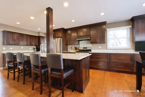 a kitchen with stainless steel appliances kitchen island granite countertop a table chairs sink and cabinets