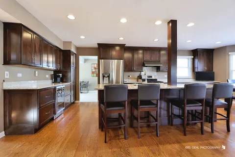 a kitchen with stainless steel appliances kitchen island granite countertop a table chairs sink and cabinets