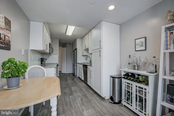 a kitchen with stainless steel appliances kitchen island granite countertop a table chairs in it and wooden floors