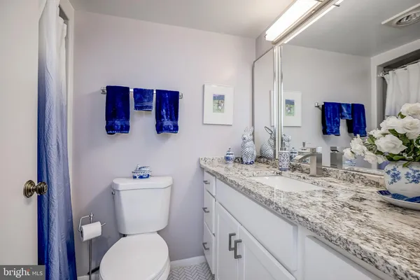 a bathroom with a granite countertop toilet sink and mirror