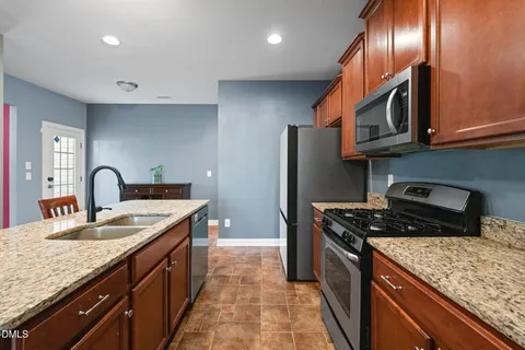 a kitchen with stainless steel appliances granite countertop a sink stove and refrigerator