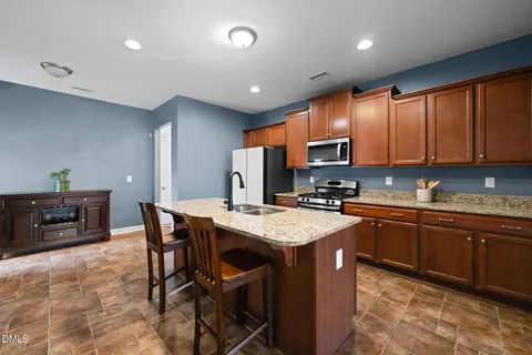a kitchen with stainless steel appliances granite countertop refrigerator a stove a sink a dining table and chairs
