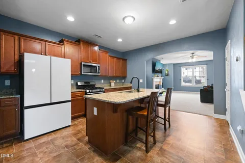 a kitchen with stainless steel appliances granite countertop a refrigerator a stove a sink a dining table and chairs