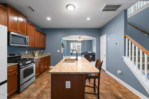 a kitchen with stainless steel appliances granite countertop a stove a sink a microwave a dining table and chairs