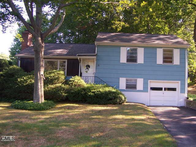 a view of a house with a yard plants and large tree
