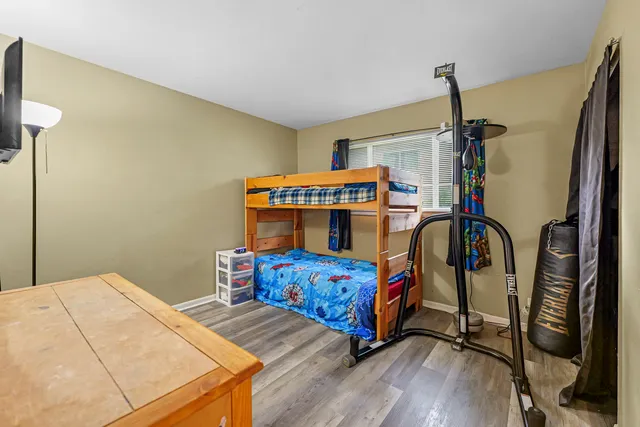 a bedroom with a bed a dresser and wooden floor