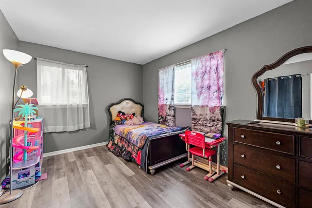 a bedroom with a bed a dresser and window