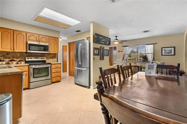 a kitchen with stainless steel appliances granite countertop a refrigerator a stove a sink a dining table and chairs with wooden floor