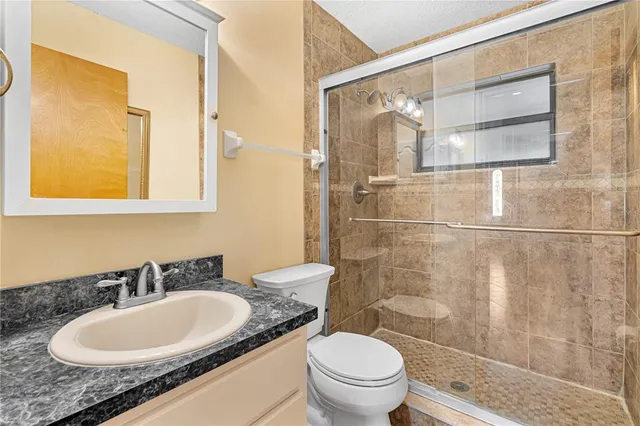 a bathroom with a granite countertop sink toilet and shower