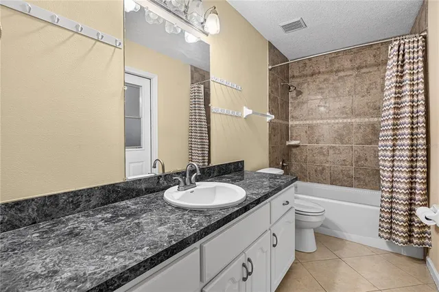 a bathroom with a granite countertop sink a toilet a mirror a bathtub and shower