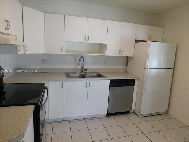 a kitchen with a refrigerator sink and cabinets