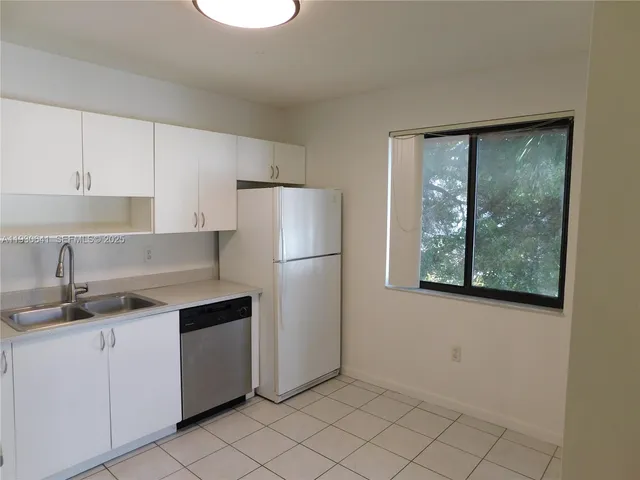 a kitchen with a sink a refrigerator and cabinets