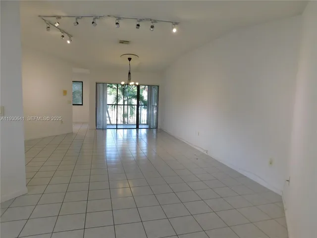 an empty room with wooden floor and chandelier