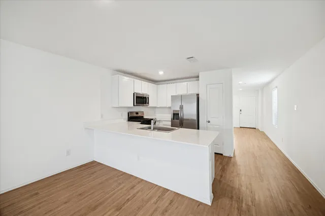 a view of a kitchen with stainless steel appliances a refrigerator cabinets and wooden floor