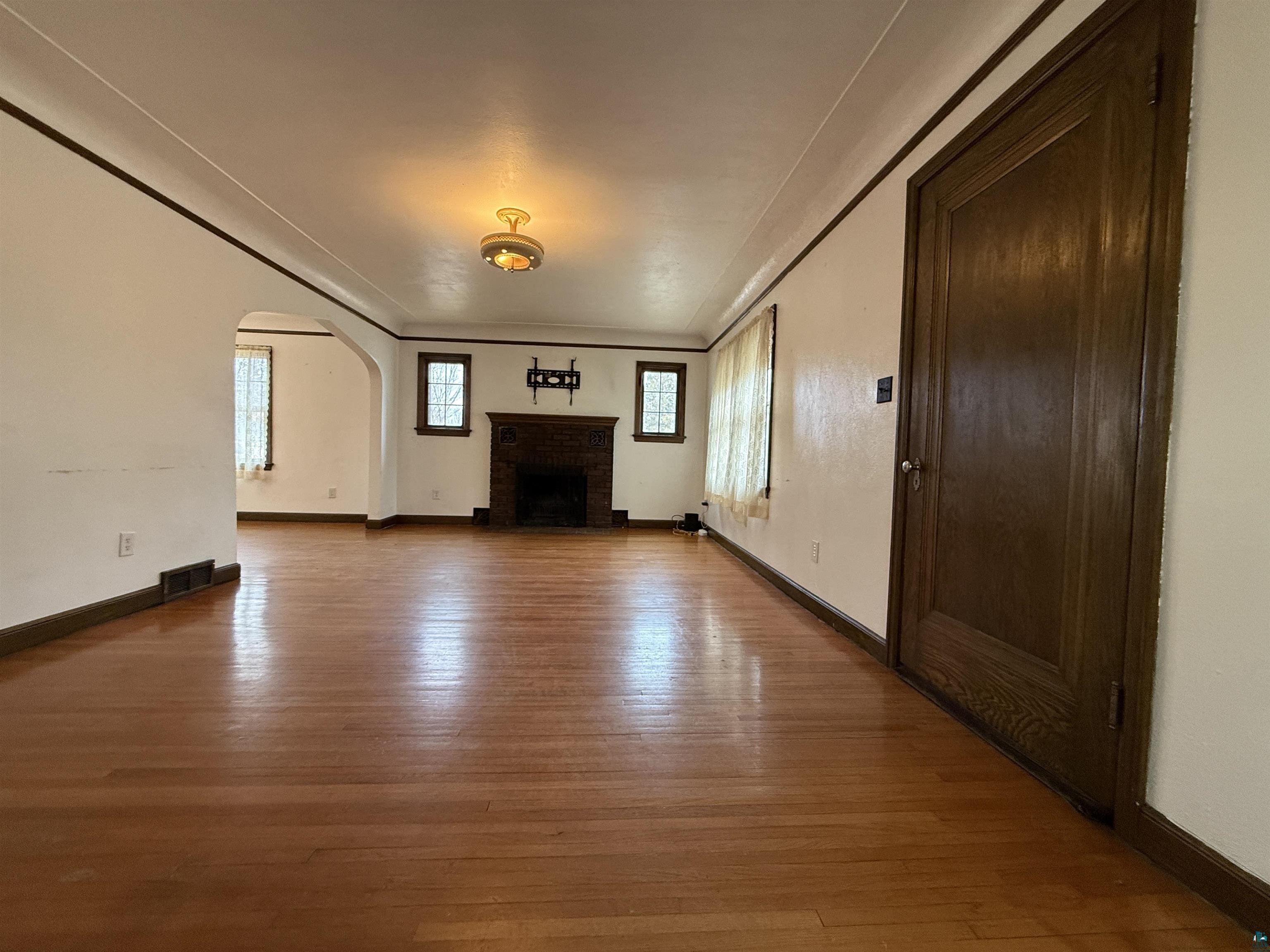 3001 3rd Avenue West Hibbing, MN 55746 - Photo 8 of 38 Unfurnished living room with light wood-type flooring, arched walkways, and a fireplace