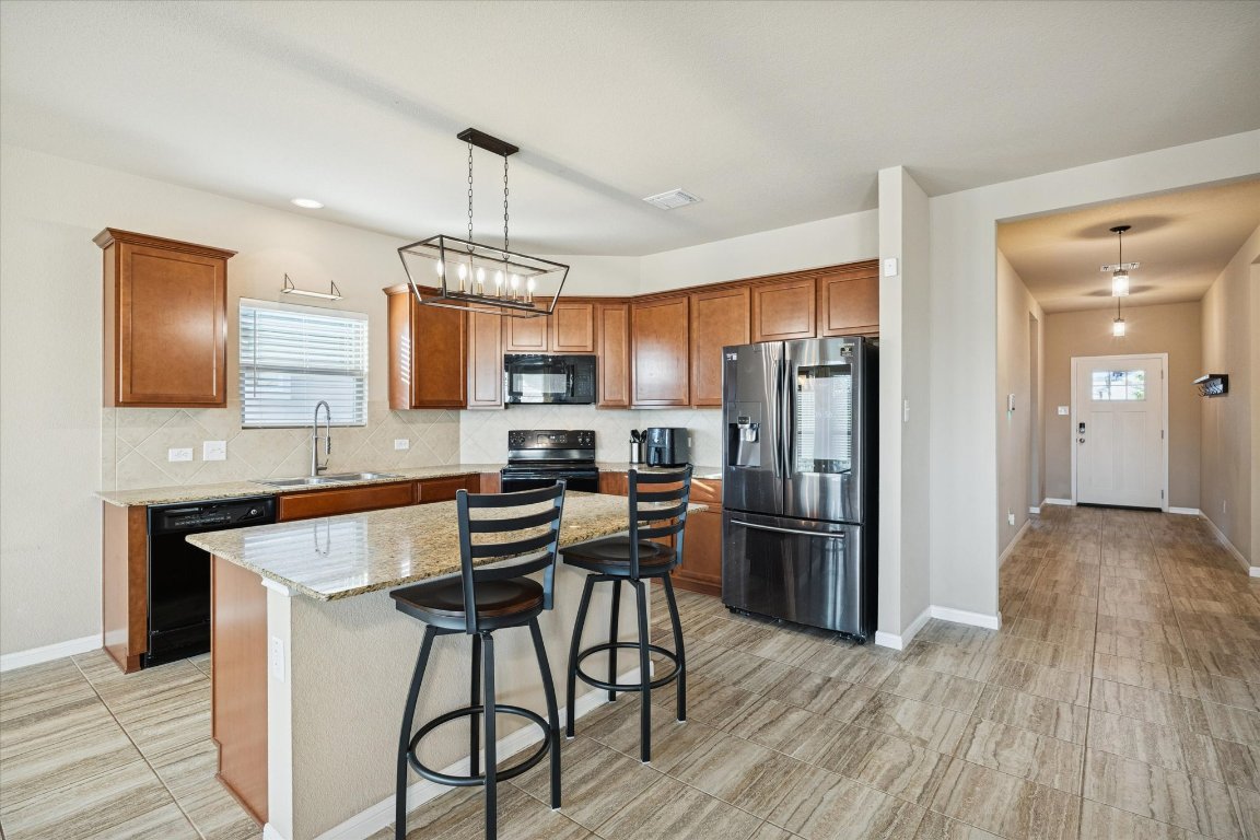 7517 Hickman Street Temple, TX 76502 - Photo 3 of 16 a kitchen with stainless steel appliances kitchen island a refrigerator and wooden floor