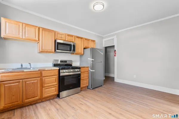 a kitchen with stainless steel appliances granite countertop a stove a sink dishwasher and a refrigerator with wooden floor