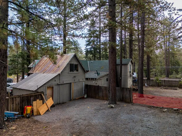 a view of a house with a wooden fence and a large tree