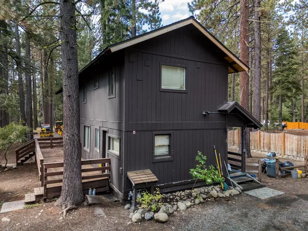 a view of a house with a yard fire pit and trees