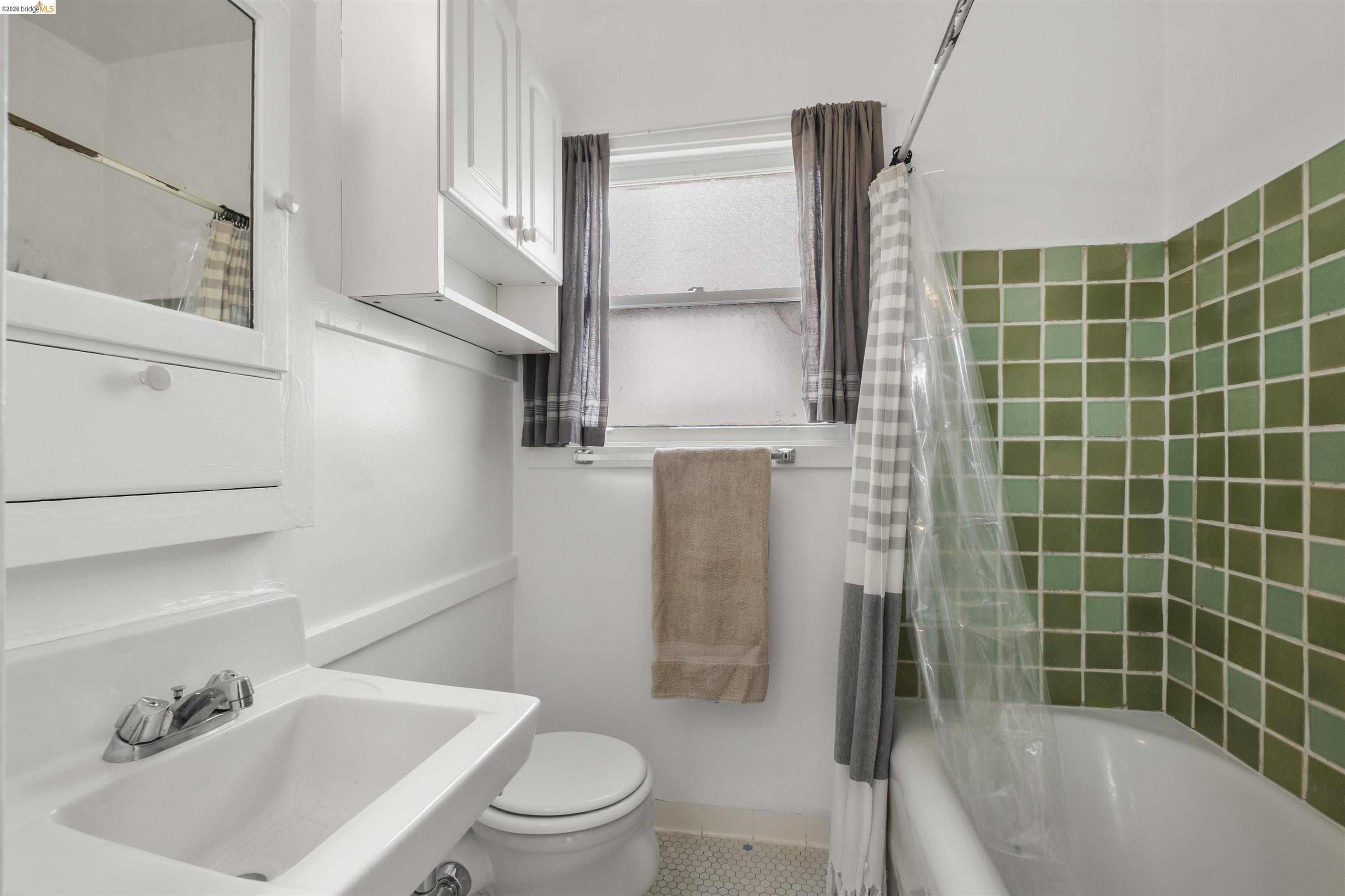 2444 Virginia Street, Unit B Berkeley, CA 94709 - Photo 36 of 39 Bathroom featuring a white pedestal sink with chrome faucet, a built-in medicine cabinet with mirrored door, and green square tile surrounding the bathtub