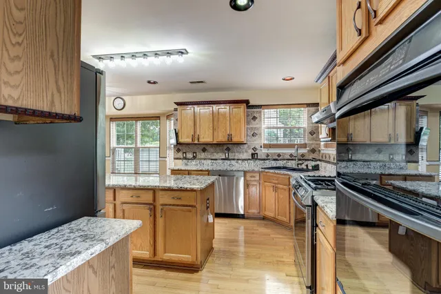a kitchen with stainless steel appliances granite countertop a stove a sink dishwasher and a refrigerator