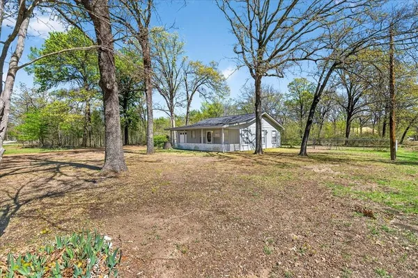 a backyard of a house with large trees and outdoor seating