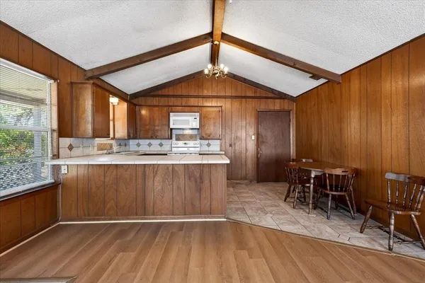 a kitchen with a table chairs wooden floors and a view of living room