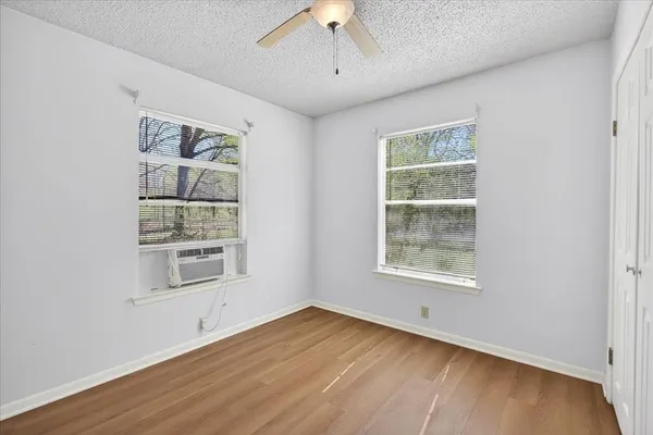 a view of an empty room with a window and wooden floor