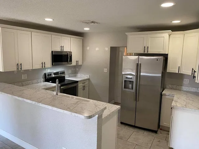 a kitchen with stainless steel appliances a refrigerator a stove a microwave a sink and a refrigerator