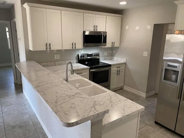a kitchen with granite countertop a refrigerator and a stove top oven